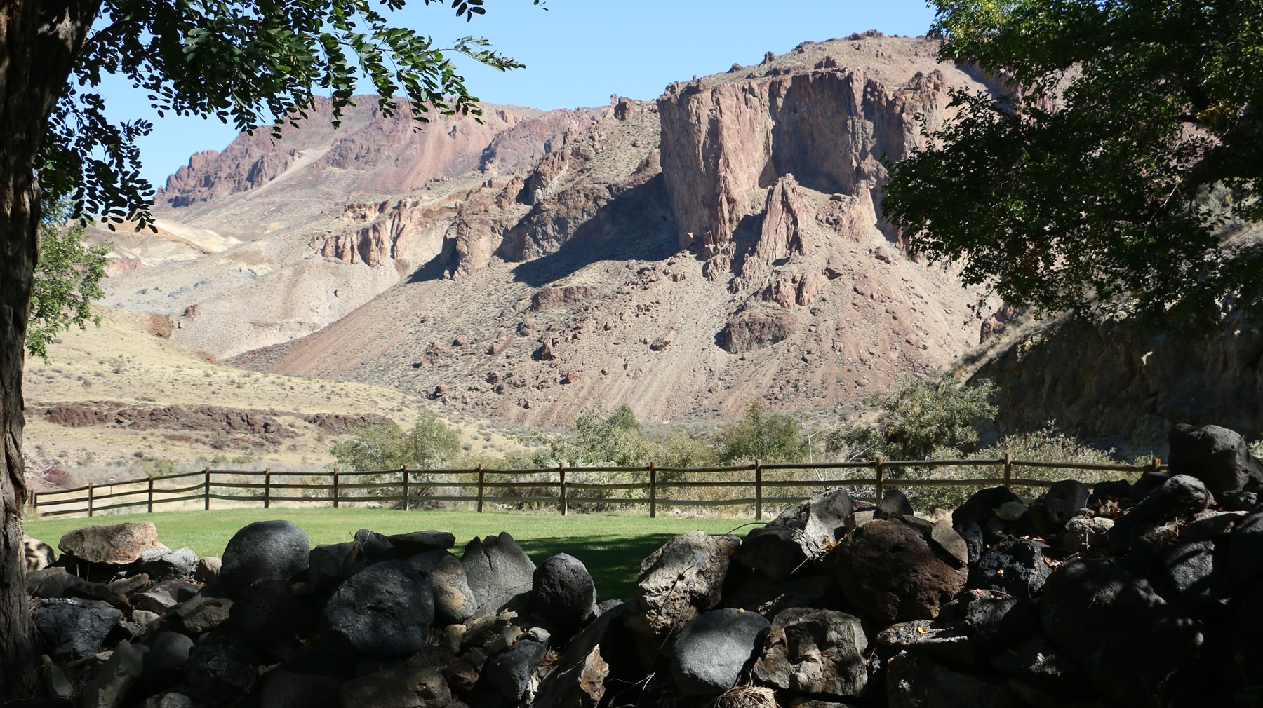 Birch Creek Historic Ranch cabin and weathered corrals beneath towering red rock spires in the Owyhee canyonlands