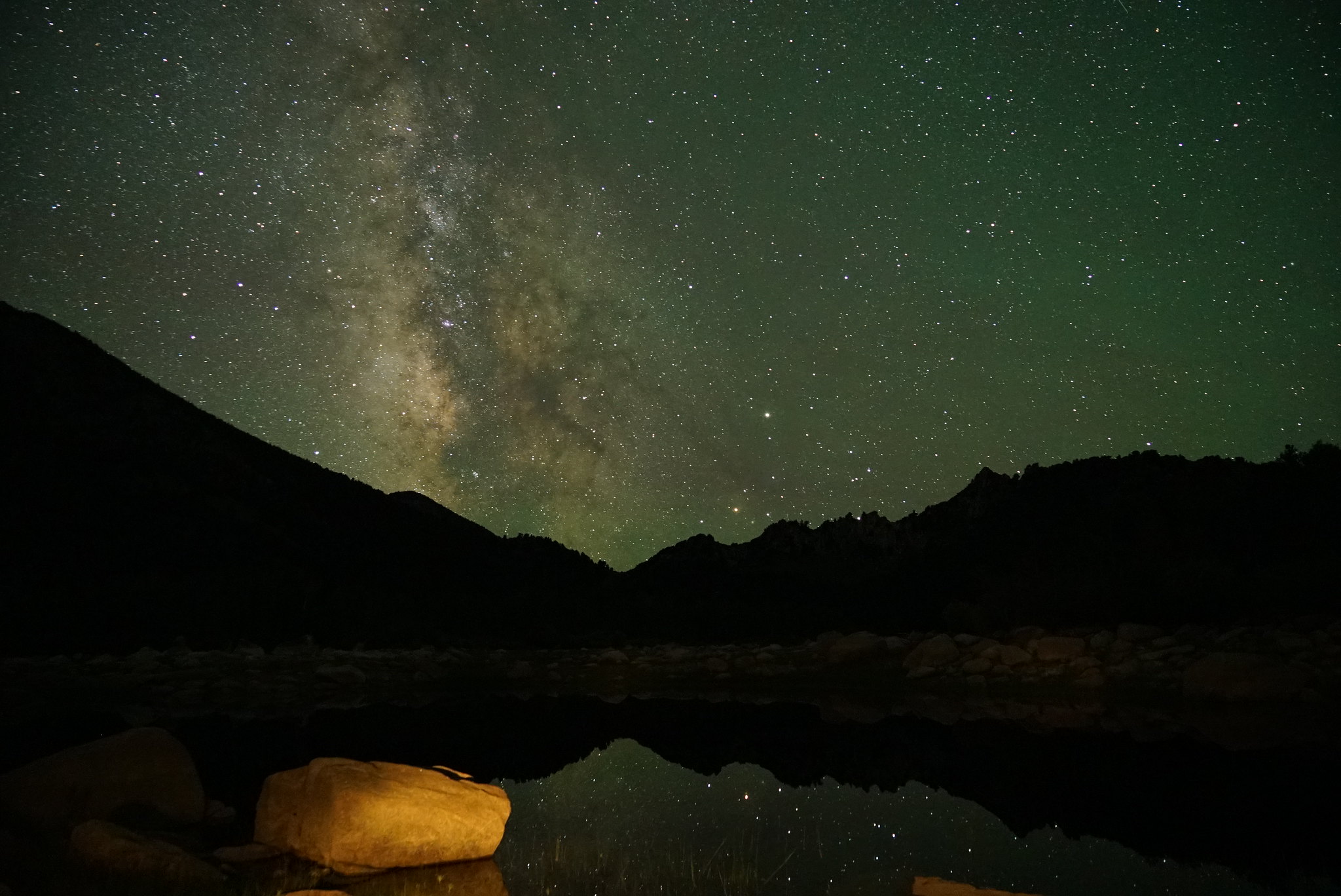 A dense field of stars and the bright core of the Milky Way over a dark desert horizon