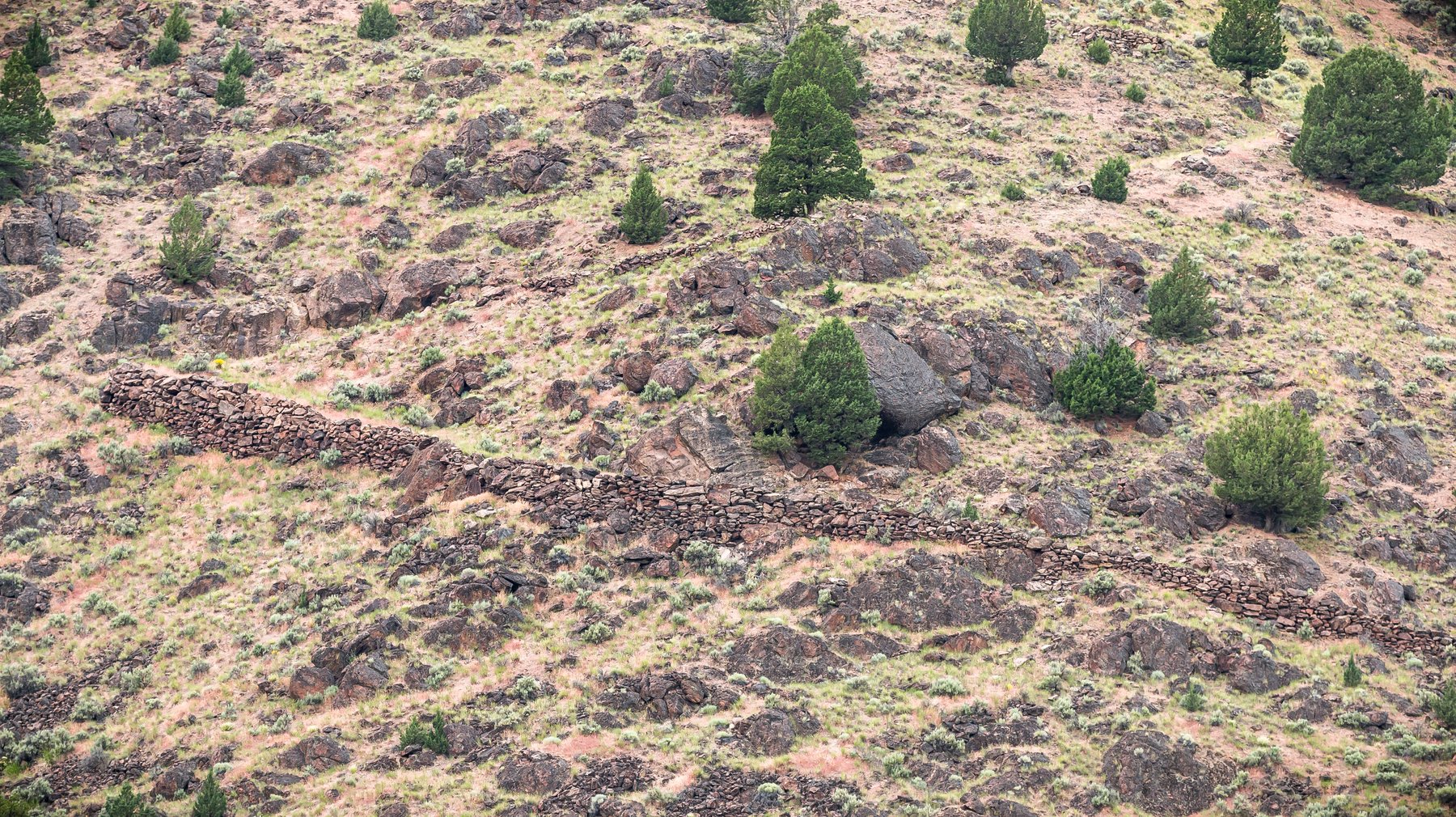 Historic stone wall and old military road climbing the canyon's west side above Three Forks